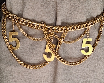 Impresionante cinturón de cadena vintage, tono dorado con accesorios de 5s en la cadena.