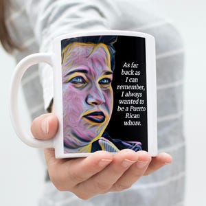 May include: White ceramic mug featuring a colorful portrait and the text: "As far back as I can remember, I always wanted to be a Puerto Rican whore." The mug is held by a person.