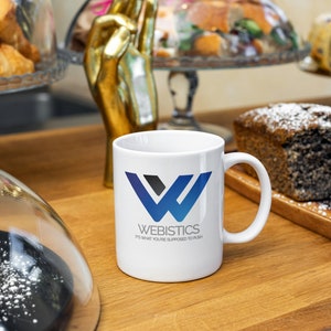 Sopranos-themed Webistics coffee mug on a café counter surrounded by pastries. Features Tony Soprano quote. Great gift idea for The Sopranos fans and lovers of mafia TV memorabilia.