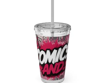 May include: A clear plastic tumbler with a lid and straw featuring a vibrant graphic design. The print displays the text COMICS AND in bold white and pink lettering against a black and pink splattered background with comic book motifs.