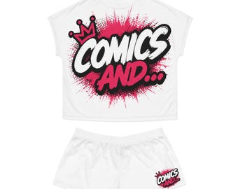 May include: A white short-sleeve t-shirt and matching shorts set. The shirt features a large graphic with a pink crown and the text "COMICS AND..." in black and pink with a spray paint effect. The shorts have a smaller version of the same graphic.
