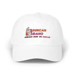 May include: White baseball cap with an embroidered logo that says "Duncan Idaho" and "Arrakis runs on Duncan". The logo features a stylized coffee cup with a pink and orange donut.