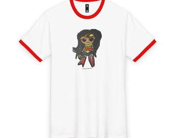 May include: A white ringer t-shirt with red trim on the collar and sleeve cuffs. The center features a cartoon illustration of a character with long black hair, a red top with a gold emblem, a blue skirt, and red boots. The text "COMICS-ART.COM" is below.