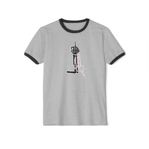 May include: Gray ringer t-shirt with black trim featuring a skeletal hand giving the middle finger. Below the hand is the word "superpowered" in a vertical script, and a pair of scissors.