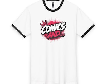 May include: A white short-sleeved ringer t-shirt with black trim on the collar and sleeve cuffs. The center of the chest features a graphic with a pink crown and the text "COMICS AND..." in a bold, stylized font over a pink spray paint effect.