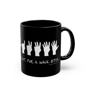 Peut inclure: Mug en céramique noire avec des illustrations de mains blanches et le texte "Walk Out. For. A. Walk. Bitch." La tasse a une poignée incurvée et une finition brillante. Le motif est imprimé sur le devant.