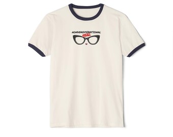 May include: A cream-colored ringer t-shirt with dark navy blue trim on the collar and sleeve cuffs. The chest features a graphic of black cat-eye glasses with the text NONDENOMINATIONAL in black and the word NERD in red lettering underneath.