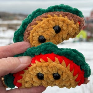 May include: Two crocheted taco plushies with green and red trim and black button eyes.