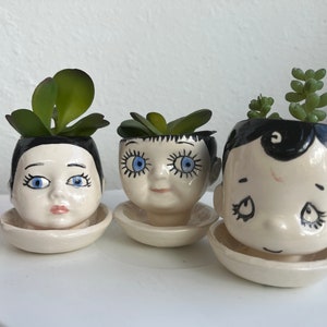 Three little ceramic doll head planters