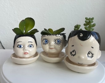 Three little ceramic doll head planters