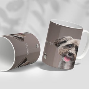 May include: Two white ceramic mugs with a brown background and a picture of a Shih Tzu dog. The text "Shih Tzu" is printed on the mugs.