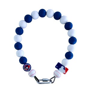 May include: A blue and white beaded necklace with baseball charms. The charms feature the Toronto Blue Jays and Major League Baseball logos.