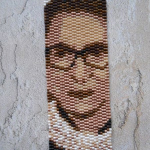 May include: A beaded portrait of a person wearing glasses and a white collar. The portrait is made with small, colorful beads.