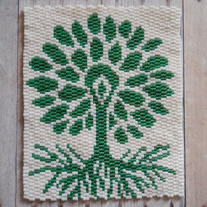 May include: A white and green beaded square with a tree design. The tree has a green trunk and green leaves.