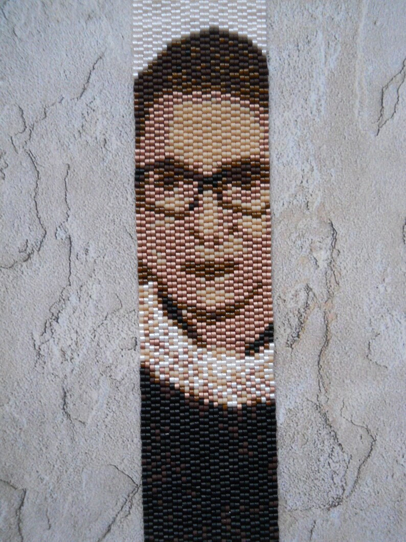 May include: A beaded portrait of a person wearing glasses and a white collar. The portrait is made with brown, black, and white beads.