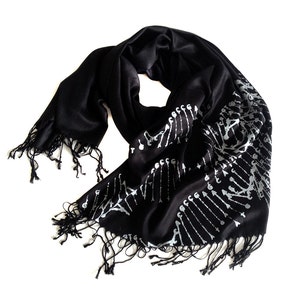 May include: Black scarf with a white skeletal design. The scarf has fringe on the ends.