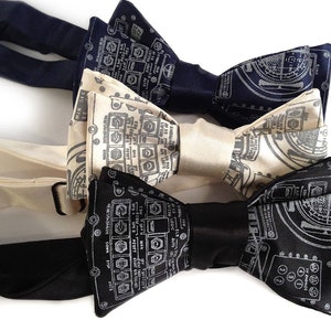 May include: Three bow ties with a circuit board design. The bow ties are black, white, and cream.