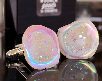 May include: A pair of iridescent white agate cufflinks with a silver backing. The cufflinks are in a black box with the text "Jewell & Vogue" printed on the box.