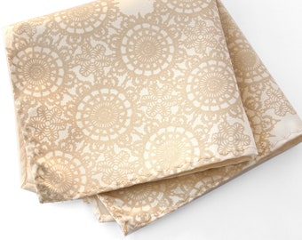 May include: A beige silk pocket square with a delicate lace pattern.