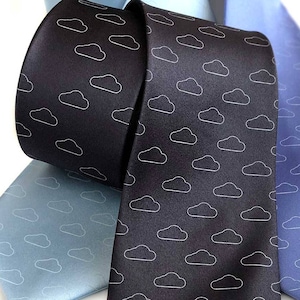 May include: Three neckties with a cloud pattern. One tie is black with white clouds, one is light blue with white clouds, and one is dark blue with white clouds.