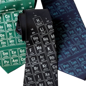 May include: Three neckties featuring a periodic table pattern. The ties are green, black and blue. The periodic table elements are printed in white.