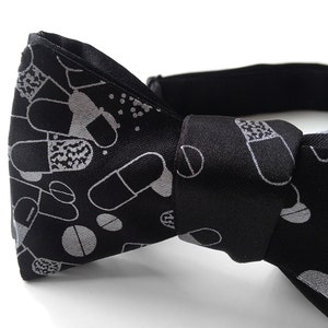 May include: Black bow tie with a silver pill pattern.