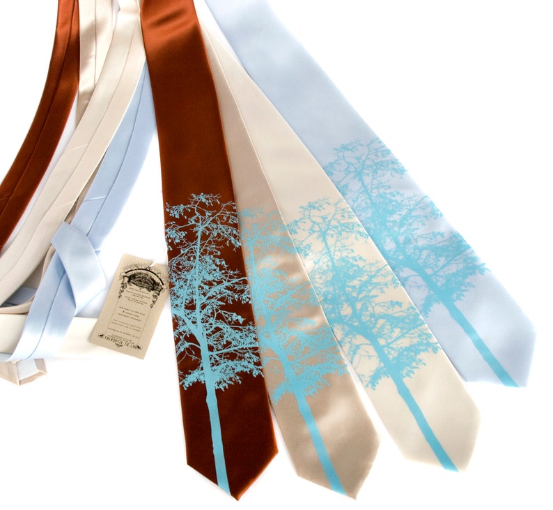 May include: Four silk ties with a blue tree silhouette design. The ties are in shades of brown, beige, and light blue.