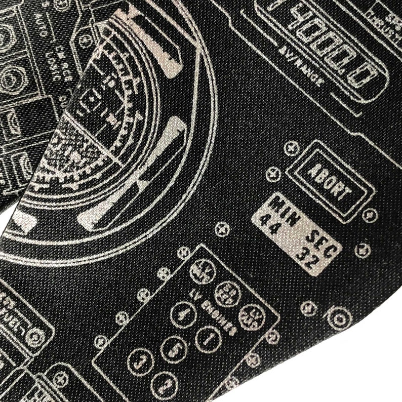 Puede incluir: Un dise&ntilde;o gr&aacute;fico en blanco y negro de un panel de control de nave espacial con un dial circular, botones y texto que dice "AUTO LOSIC DU", "CM RCE", "D", "4000.0", "AV/RANGE", "ABORT", "MIN SEC", "44", "32", "VEL", "LV ENGINES".