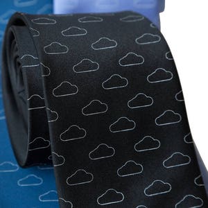 May include: A black silk tie with a white cloud pattern. The tie is rolled up and partially visible.