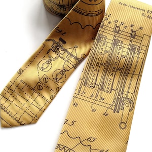 May include: A gold tie with a brown printed design of a technical drawing. The drawing includes the text "Zu der Patentschrift 579 Kl. 42b".