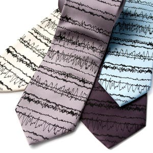 May include: Three silk ties with a black and white wave pattern. The ties are in shades of light gray, blue, and purple.