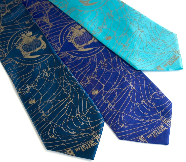 May include: Three silk ties with a weather map design in gold on a blue, teal, and dark blue background. The ties have the text "AVIATION STREAM" printed on the bottom.