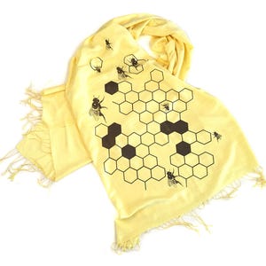 May include: A yellow silk scarf with a black and white honeycomb pattern and brown bees.