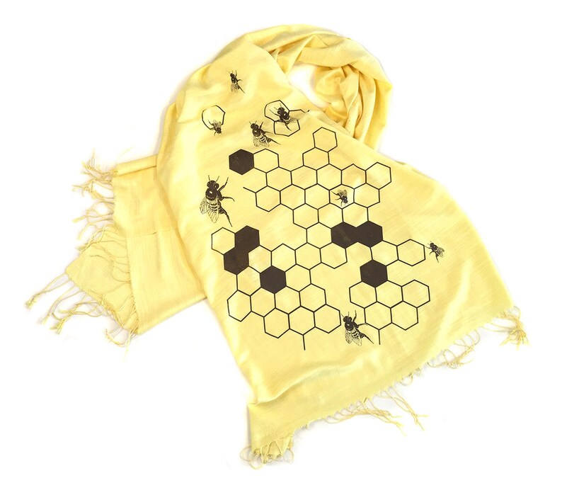 May include: A yellow silk scarf with a black and white honeycomb pattern and brown bees.