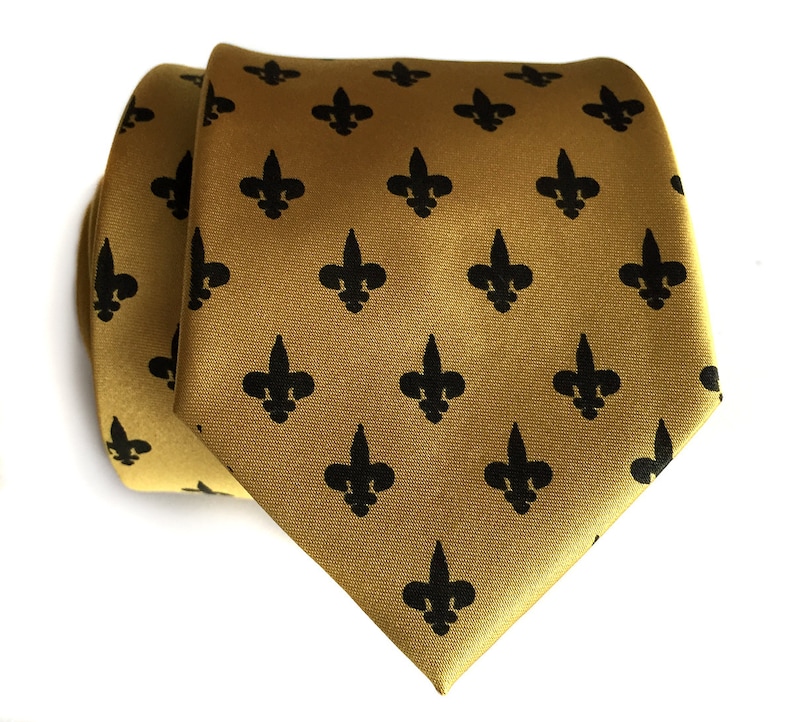 May include: A gold tie with a black fleur-de-lis pattern.