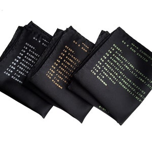 Puede incluir: Tres pa&ntilde;uelos de bolsillo de seda negra con texto blanco y dorado. El texto en los pa&ntilde;uelos dice "64 K RAM" e incluye l&iacute;neas de c&oacute;digo.