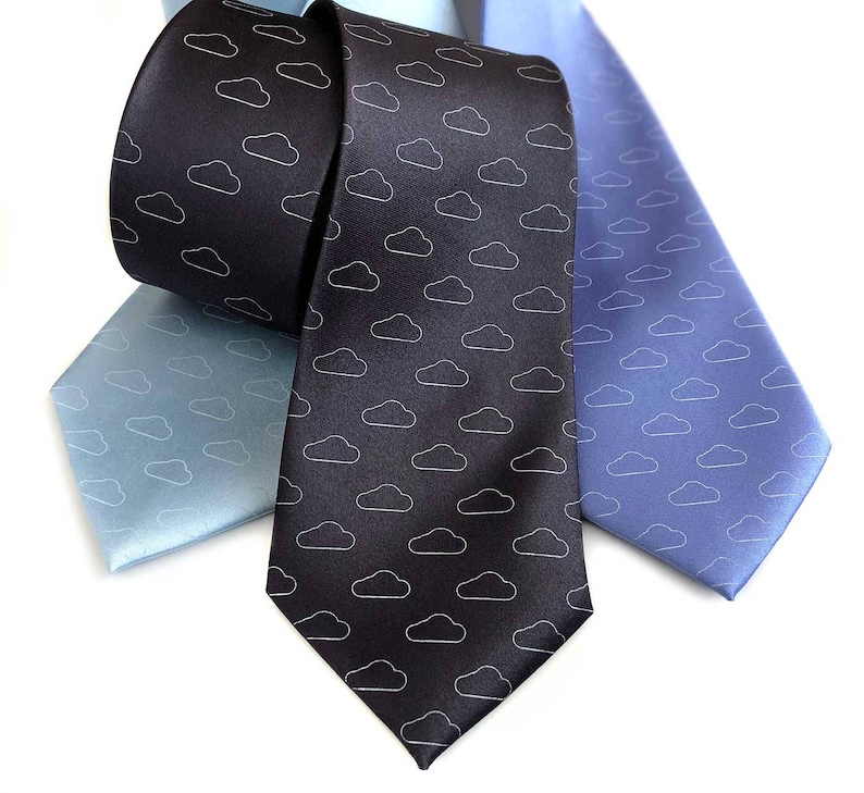 May include: Three neckties with a cloud pattern. One tie is black with white clouds, one is light blue with white clouds, and one is dark blue with white clouds.