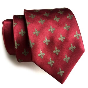 May include: A red silk tie with a repeating pattern of gold fleur-de-lis.