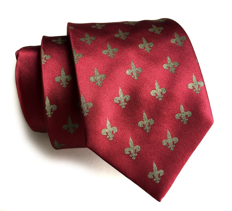 May include: A red silk tie with a repeating pattern of gold fleur-de-lis.