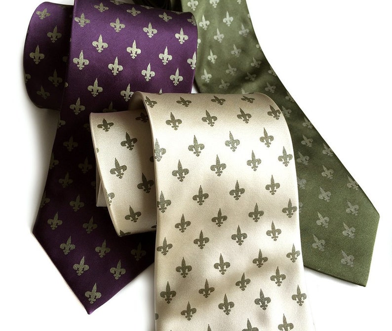 May include: Three silk ties with a fleur-de-lis pattern. One tie is purple, one is green, and one is beige.