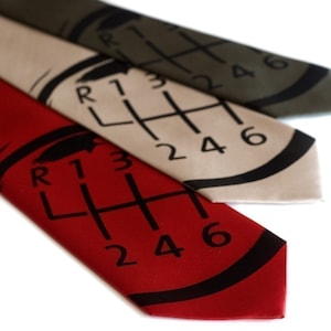 May include: Three silk ties with a gear shift pattern printed on them. The ties are red, beige, and olive green.