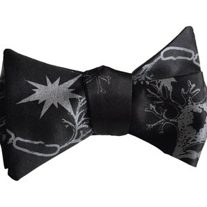 May include: A black bow tie with a silver chain and tree design.