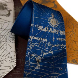 May include: Three silk neckties with a map design. The ties are in blue, white, and orange. The blue tie has a compass rose and the text "30" printed on it.