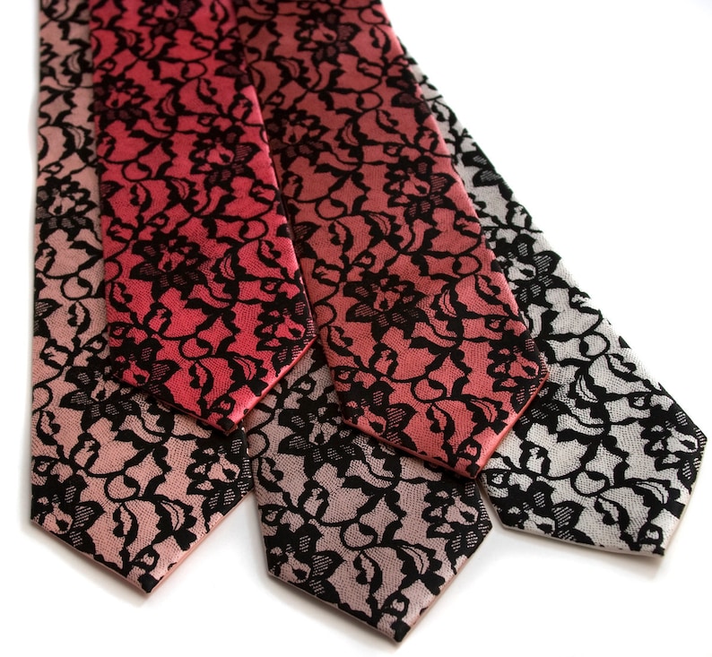 May include: Three silk neckties with a black lace pattern on a gradient background. The ties are in shades of pink, red, and gray.