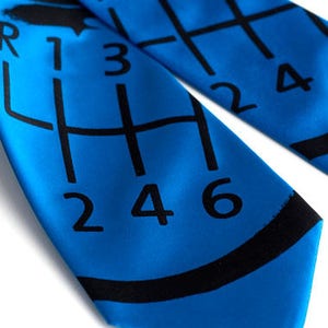 May include: A blue tie with a black gear shift pattern and the numbers 1, 2, 3, 4, 5, and 6 printed on it.