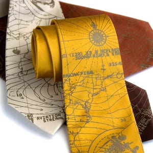 May include: Three silk ties with a map design. The ties are in brown, beige, and yellow. The map design is in a vintage style with lines and text.