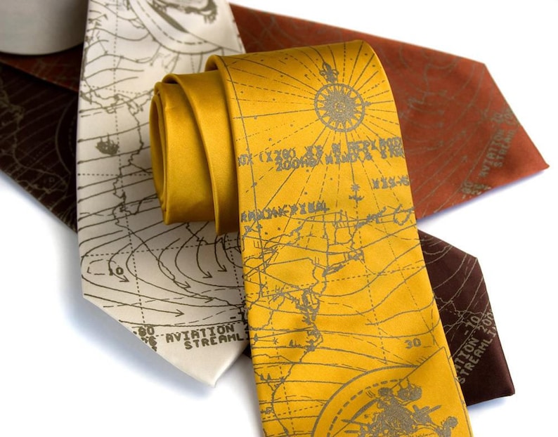 May include: Three silk ties with a map design. The ties are in brown, beige, and yellow. The map design is in a vintage style with lines and text.