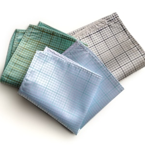 以下が含まれることがあります： 青、緑、白の色のパターンが施されたポケットチーフが3枚。チーフは折り畳まれ、白い背景の上に置かれています。