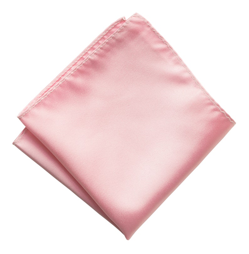 Puede incluir: Un pa&ntilde;uelo de bolsillo de sat&eacute;n rosa p&aacute;lido. El cuadrado est&aacute; doblado y tiene una textura suave y sedosa.