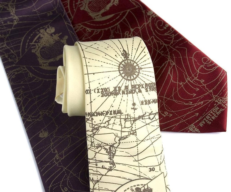 May include: Two silk neckties with a map design. One tie is burgundy with a gold map pattern. The other tie is cream with a brown map pattern. Both ties have a compass rose design.